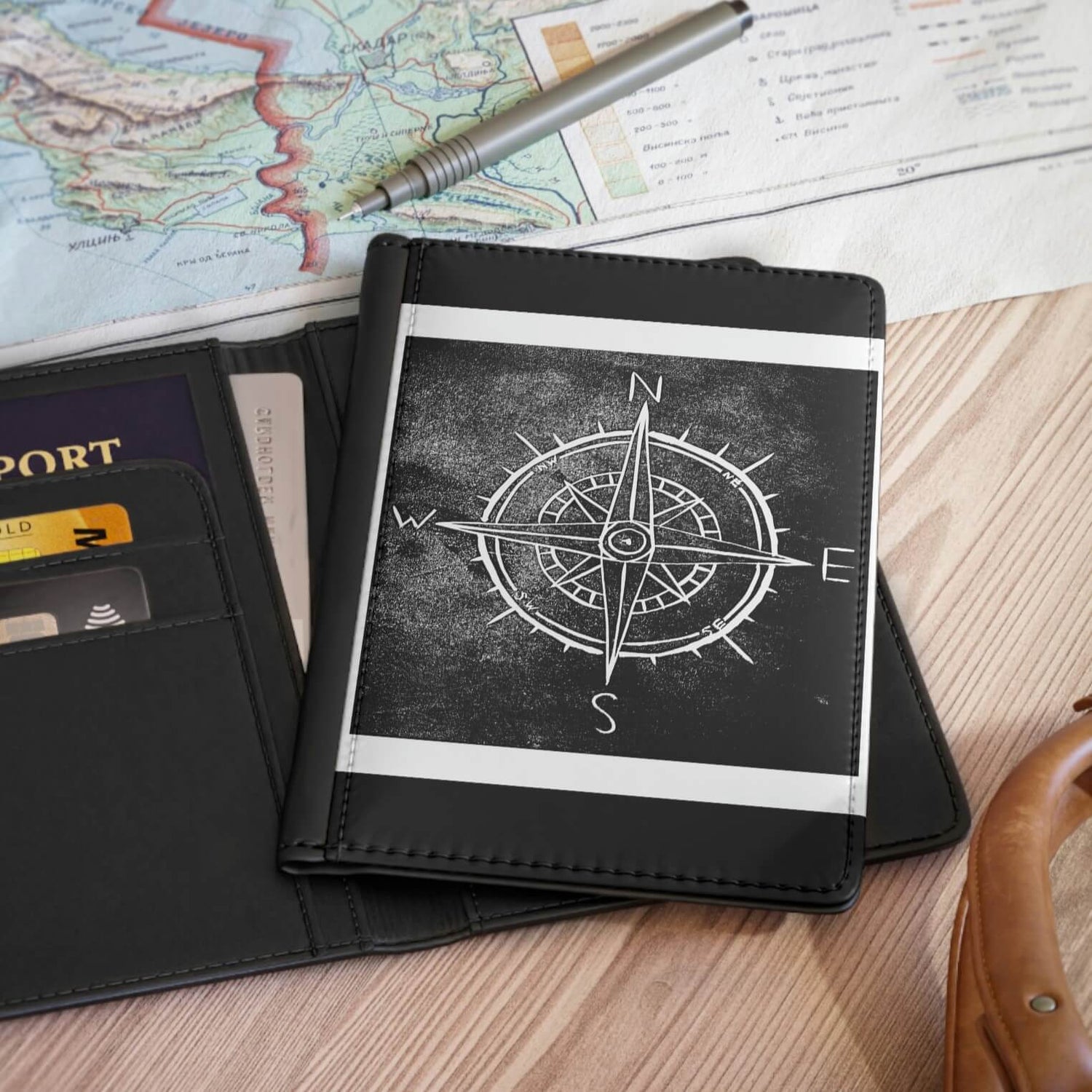 passport holder in a table top with a black digitally edited lino print of a compass on it.